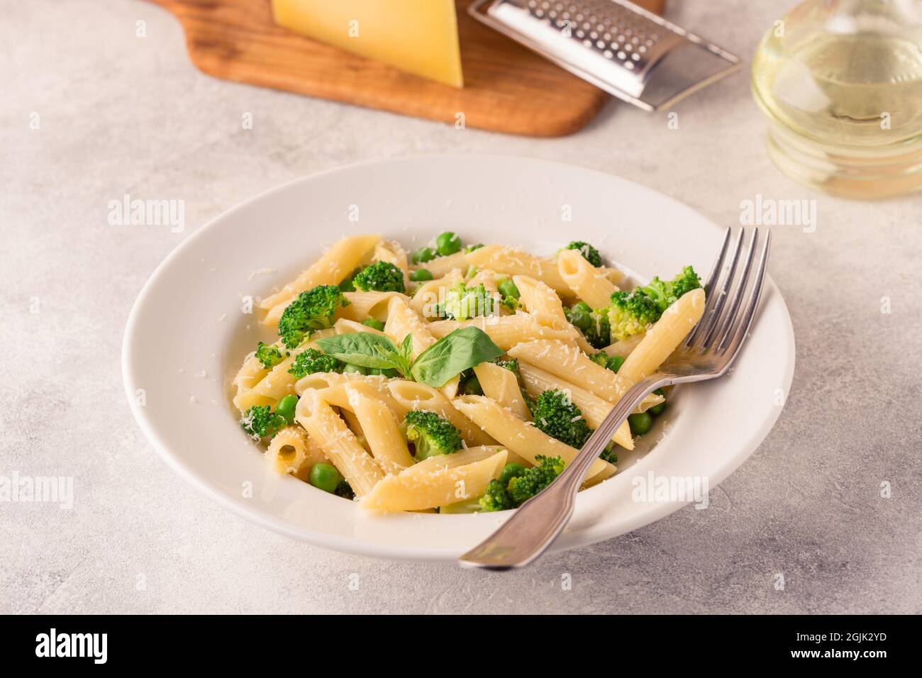 Pasta con piselli verdi, broccoli e parmigiano su sfondo chiaro. Foto Stock