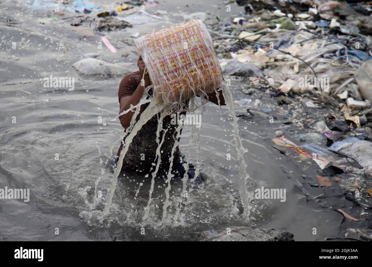 I lavoratori hanno sbattuto l'acqua di stoffa lungo un fiume inquinato. I lavoratori lavano, squillano e asciugano la stoffa lungo le rive del fiume ogni giorno per una retribuzione minima. Il 09 settembre 2021 a Dhaka, Bangladesh. (Foto di Sumit Ahmed / Eyepix Group) Foto Stock