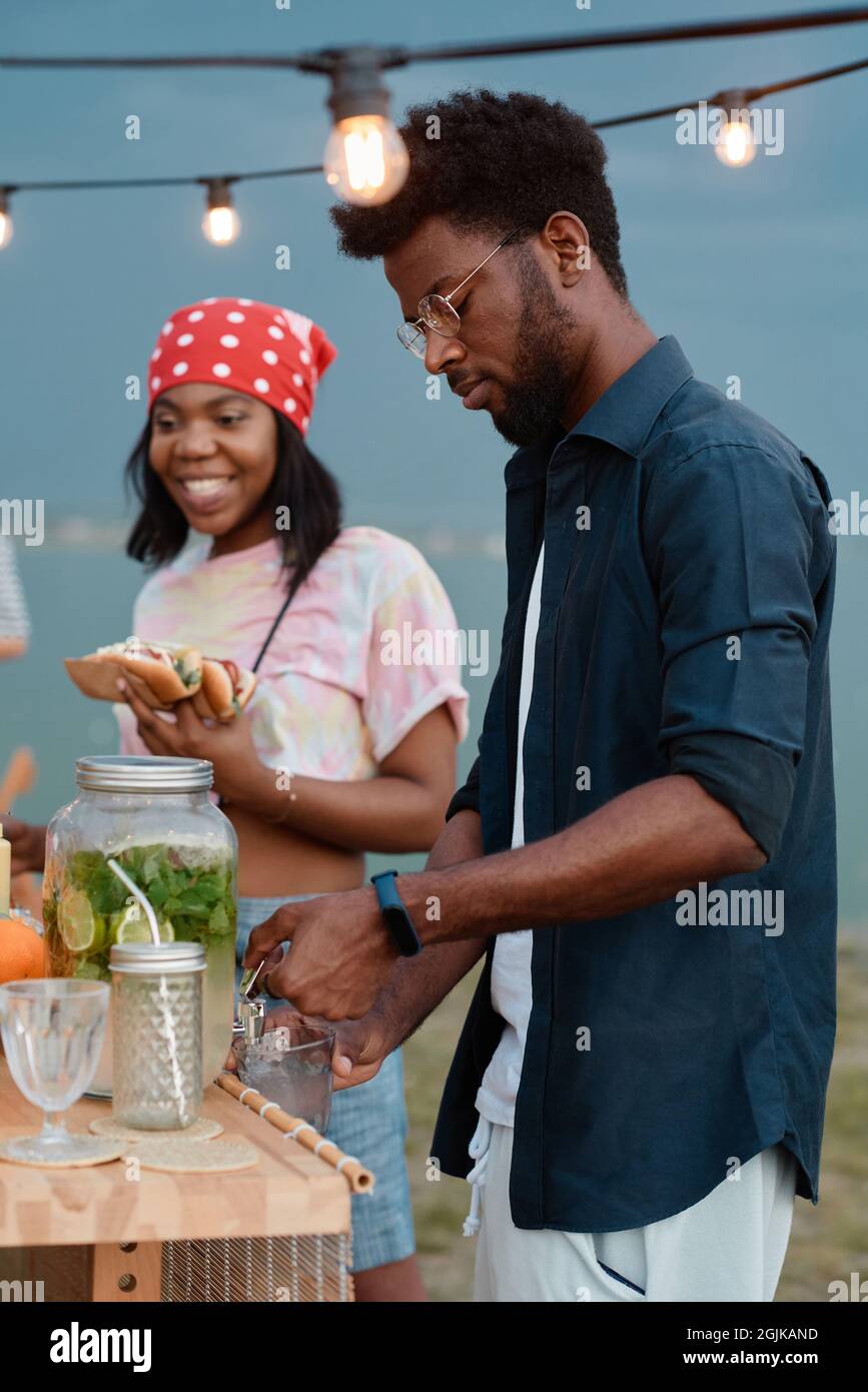 Giovane coppia africana che pranza con panini e beve limonata all'aperto Foto Stock