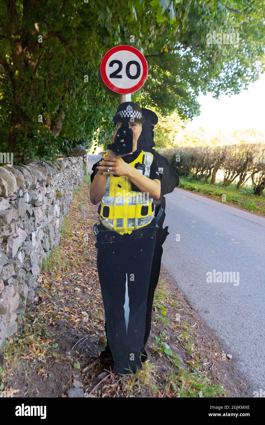 Cartoncino cut-out falso agente di polizia stradale con pistola di velocità attaccato al segnale limite di velocità 20 mph, Fortinghall, Perth e Kinross, Scozia, Regno Unito Foto Stock