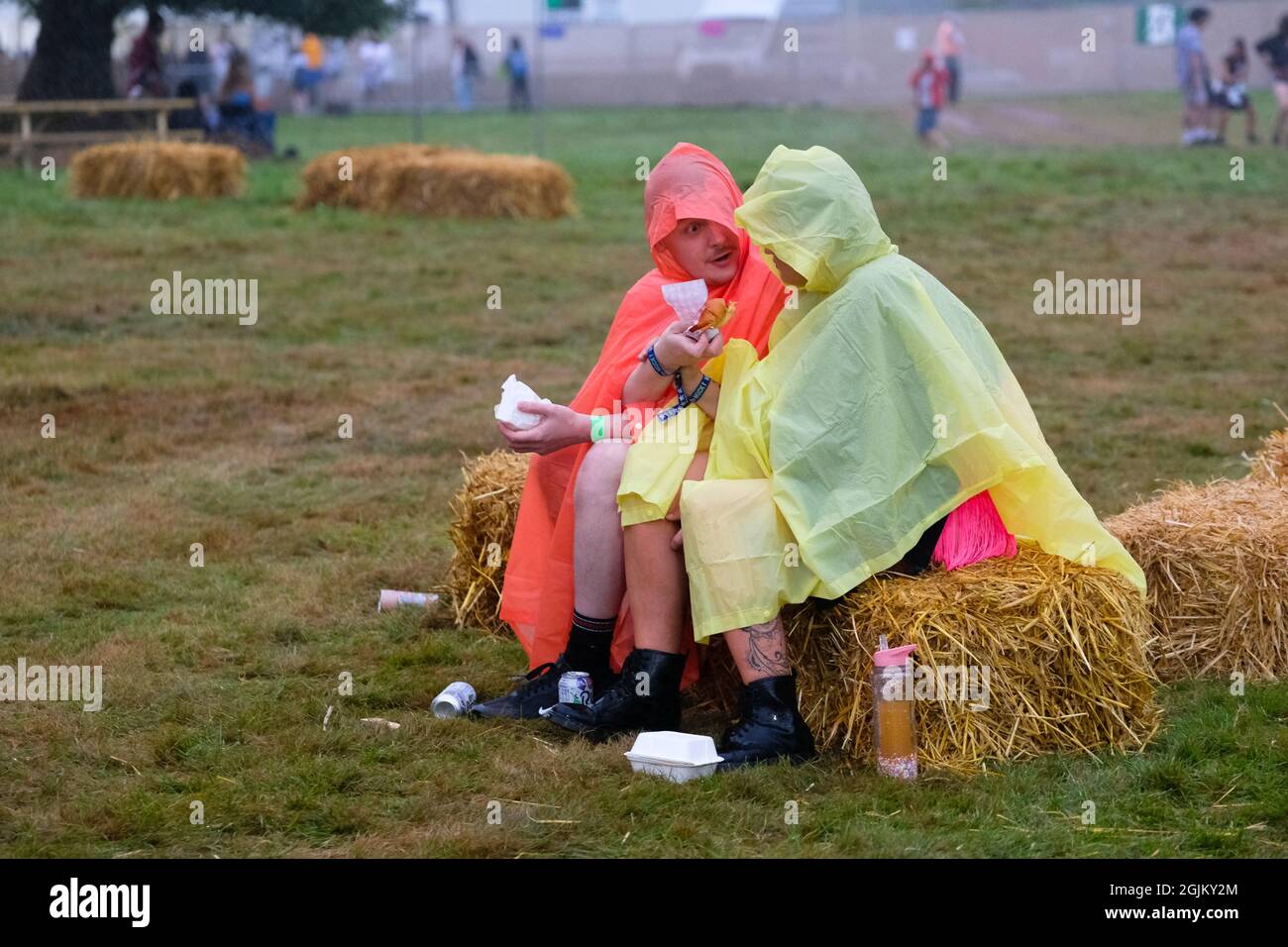 Vicarage Farm, Winchester Hampshire, Regno Unito. 10 Settembre 2021. Coppia in poncho pioggia seduta parlare, mangiare e ascoltare musica al Mucky Weekender, Hampshire credito: Dawn Fletcher-Park/Alamy Live News Foto Stock