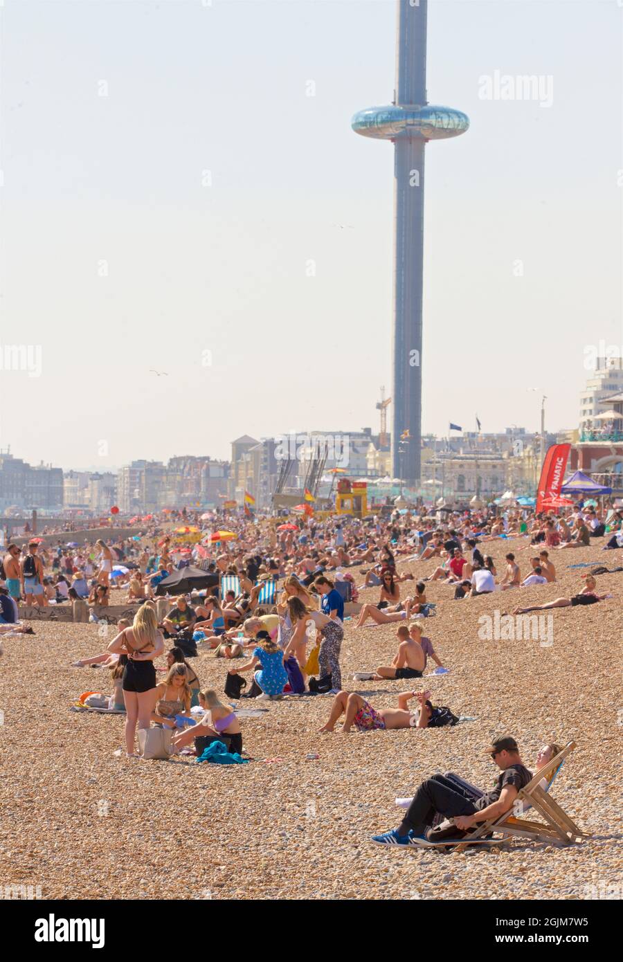 Spiagge affollate del centro di Brighton e Hove. A ovest del molo del Palazzo di Brighton. Vacanze estive. Sussex, Inghilterra, Regno Unito. I360 torreggiante sopra. Foto Stock