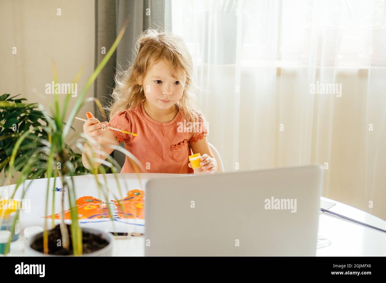 Bambina che trascorre un po' di tempo a disegnare utilizzando lezioni online su un notebook a casa. Apprendimento a distanza, formazione online. Foto Stock