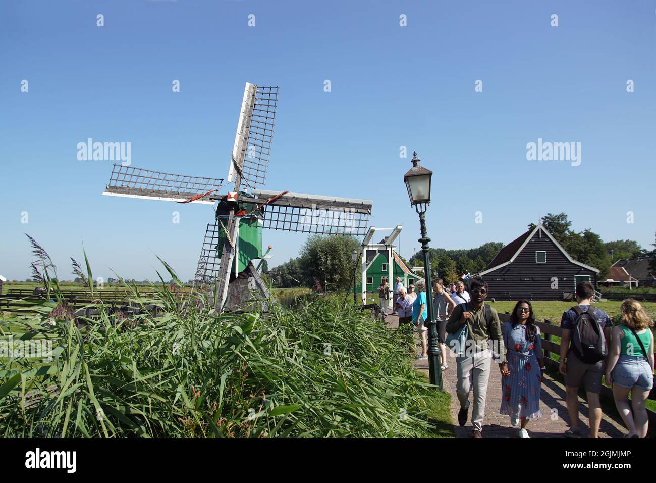 Passeggiando per i turisti su un piccolo ponte levatoio e un piccolo mulino a vento nel museo all'aperto olandese De Zaanse Schans. Zaanstad, Paesi Bassi, settembre Foto Stock