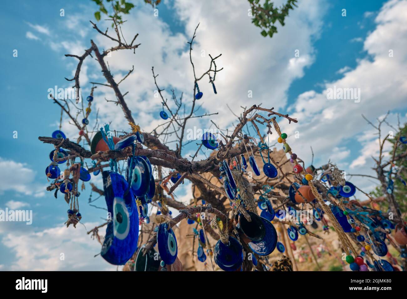 Grandi gruppi di perle blu e rotte indossate contro l'occhio malvagio appeso su alberi in bordo castello (uchisar) in Cappadocia, brulicante in Turchia con drammatico Foto Stock
