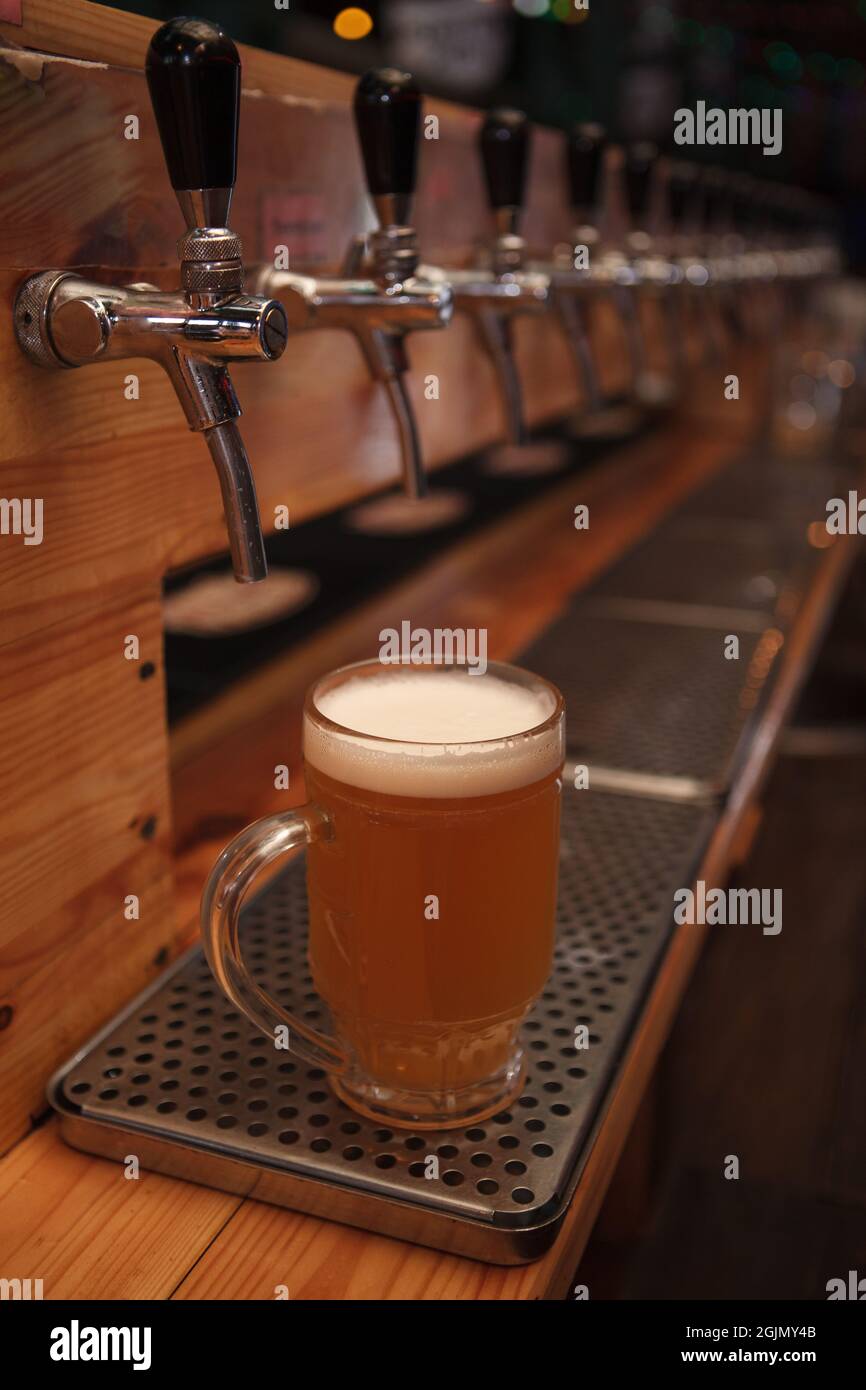 Shot verticale di bicchiere di birra al banco bar con birra alla spina Foto Stock