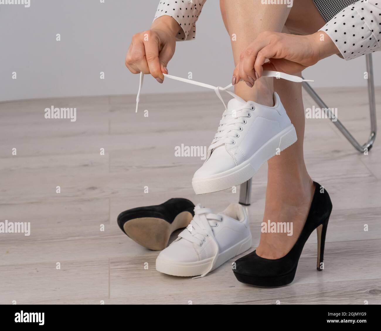 La donna di affari in primo piano toglie le sue scarpe con le sneaker in pelle bianca Foto stock Alamy