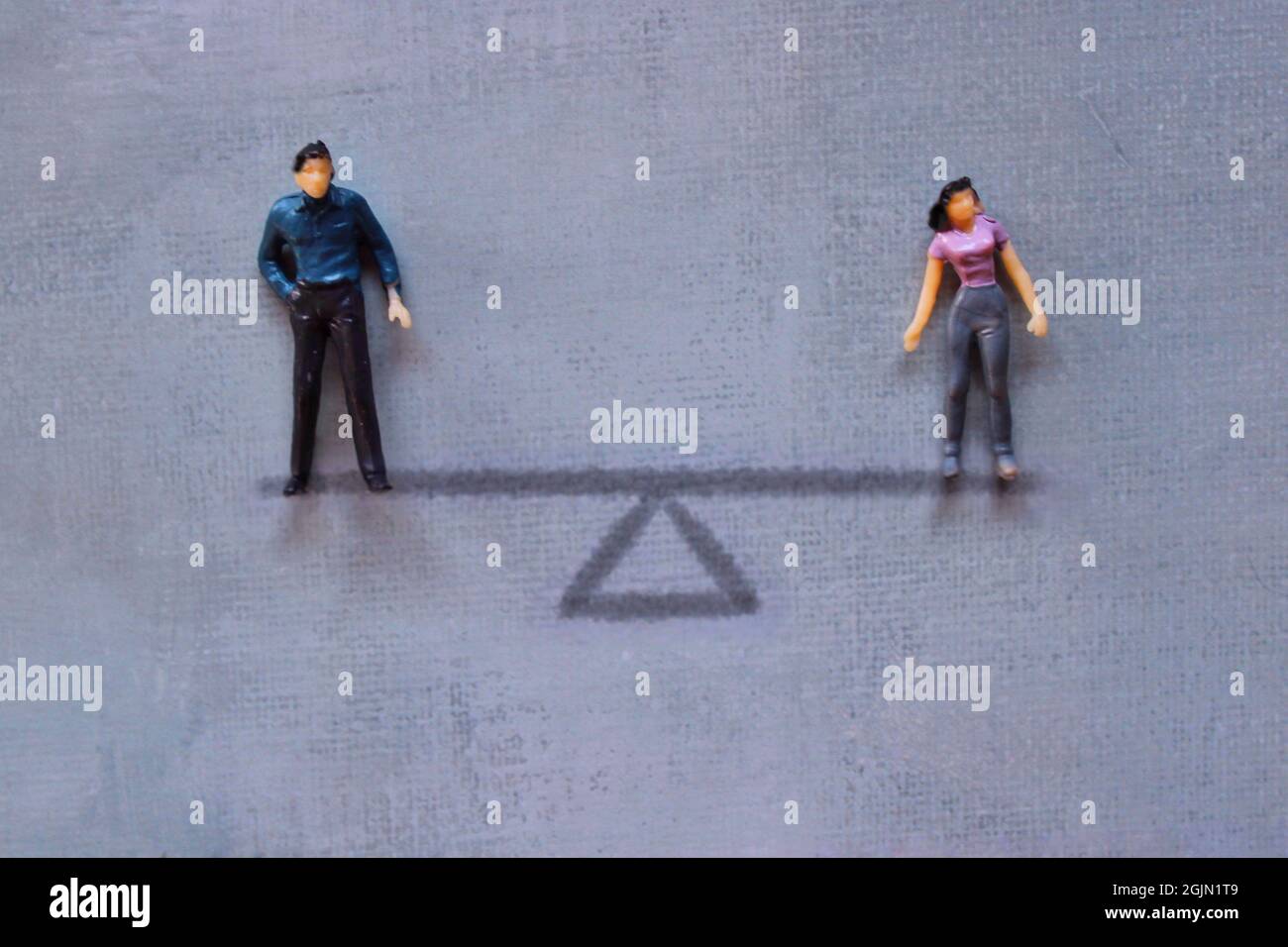 Concetto di parità di genere. Uomo e donna in miniatura in piedi su scala di equilibrio. Foto Stock