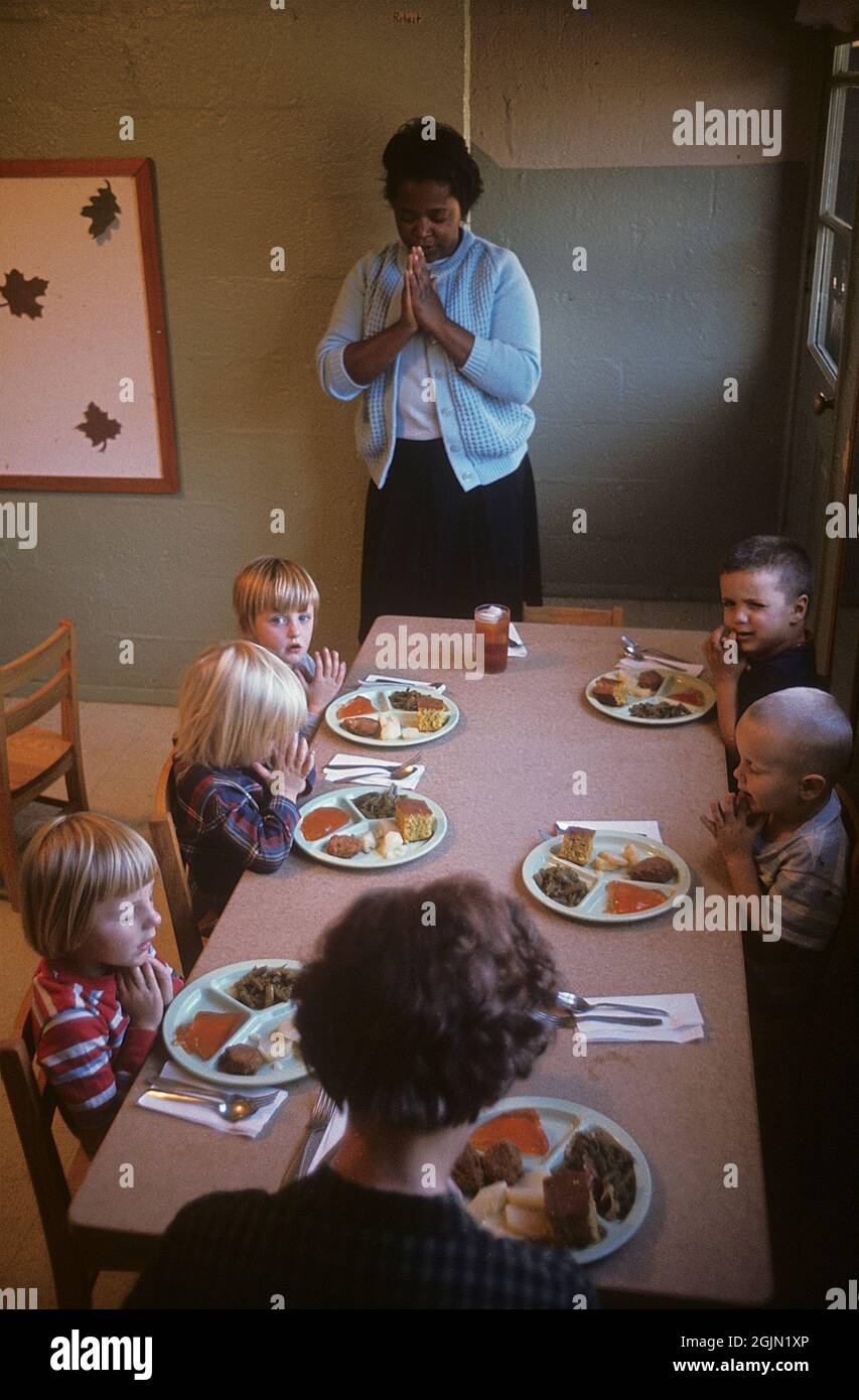 USA Alabama 1966. Un centro di assistenza al giorno in Alabama dove lavora una donna afroamericana. Dice una preghiera prima di fare un pasto insieme ai bambini bianchi. Credit Roland Palm Ref 6-6-7 Foto Stock
