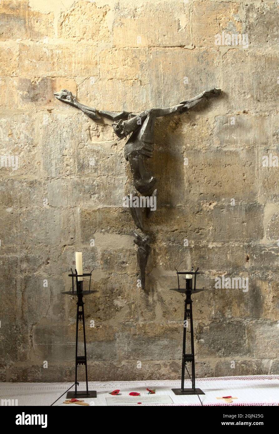 Scultura in metallo Crocifisso di Laurence Broderick in Christchurch Priory contro Un muro calcareo, Regno Unito Foto Stock