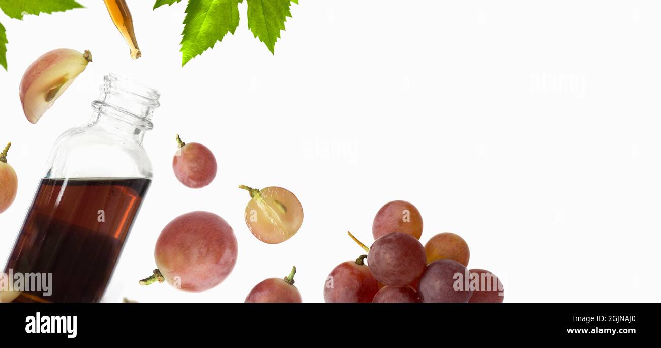 Bottiglia con olio di semi d'uva rosso su sfondo bianco. Spazio di copia, disposizione piatta, vista dall'alto. Foto Stock