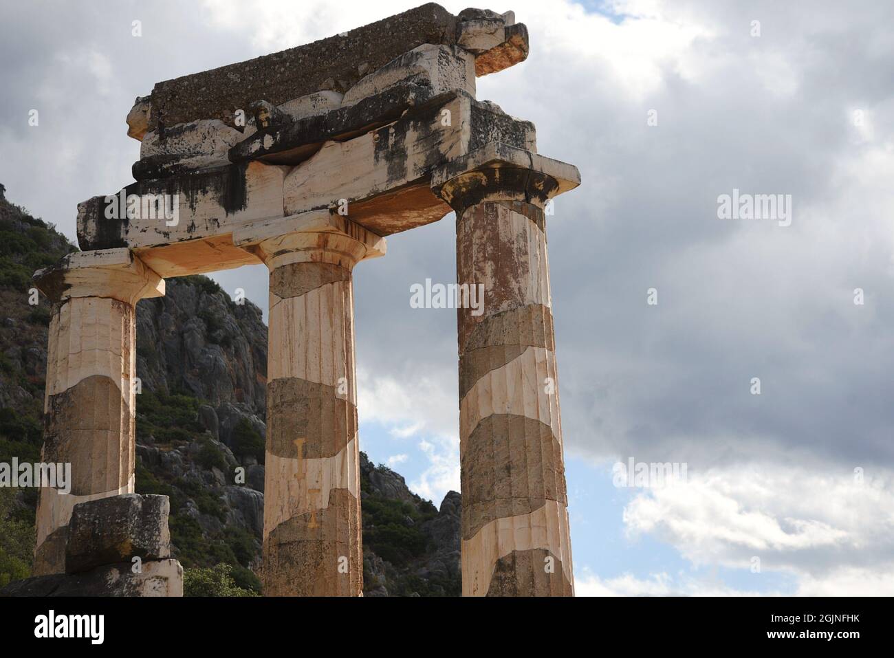 Antiche colonne dell'ordine dorico con frontone, trigliche e metope al santuario di Atena Pronaia il sito archeologico sacro di Delfi Grecia. Foto Stock