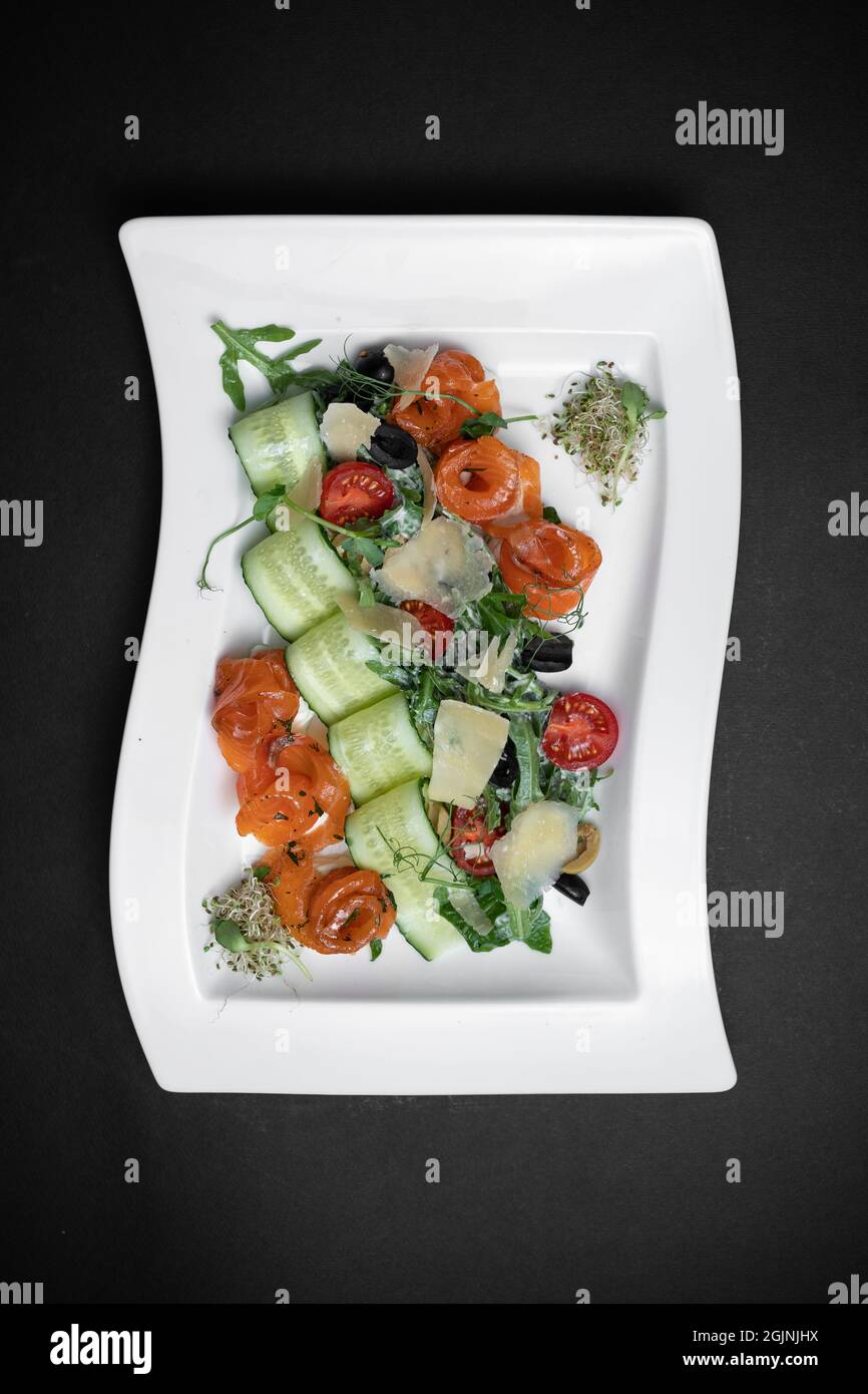 vista dall'alto dell'insalata con salmone e verdure leggermente salate su sfondo nero Foto Stock