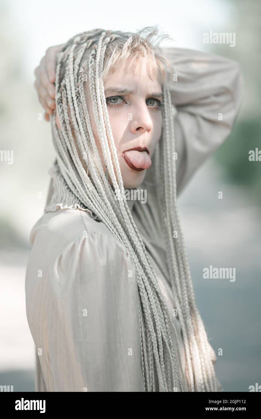 Giovane donna che mostra una lingua durante la posa, facendo un concetto di faccia scherzo Foto Stock
