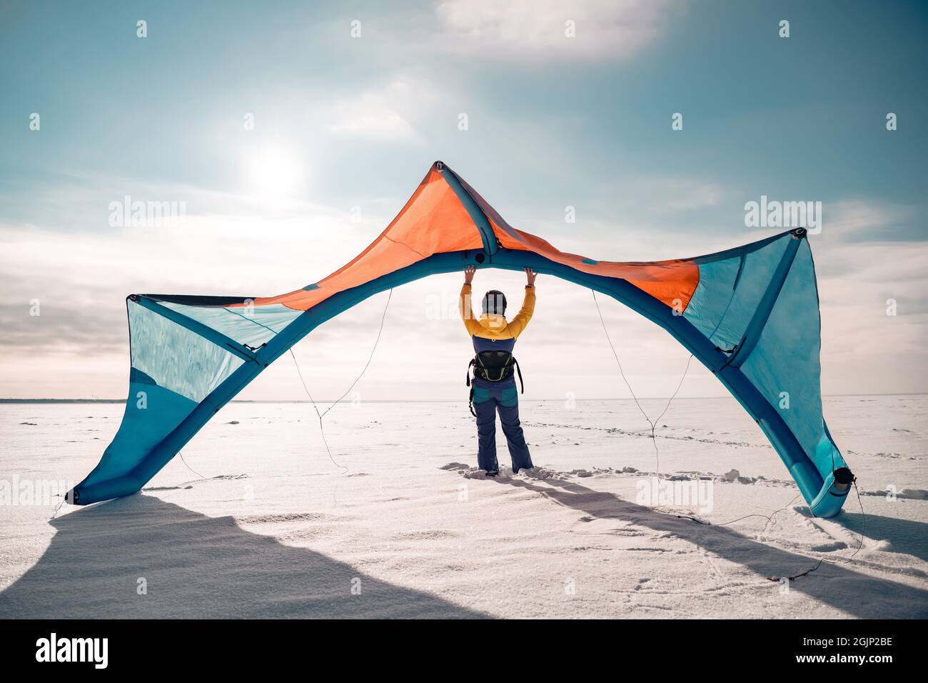 La ragazza sportiva si alza e tiene snowkite in mano. Concetto di kitesurf invernale Foto Stock