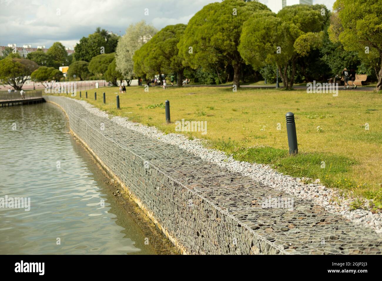 Recinzione vicino alla riva. La costa è fortificata dalle inondazioni. Forte betulla da pietre raccolte in una cornice metallica. Foto Stock