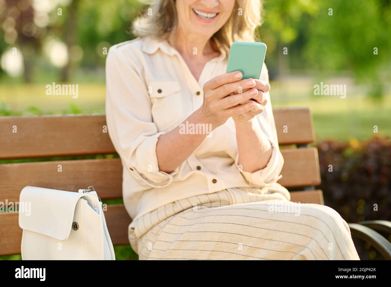 Donna sorridente con smartphone nelle mani Foto Stock