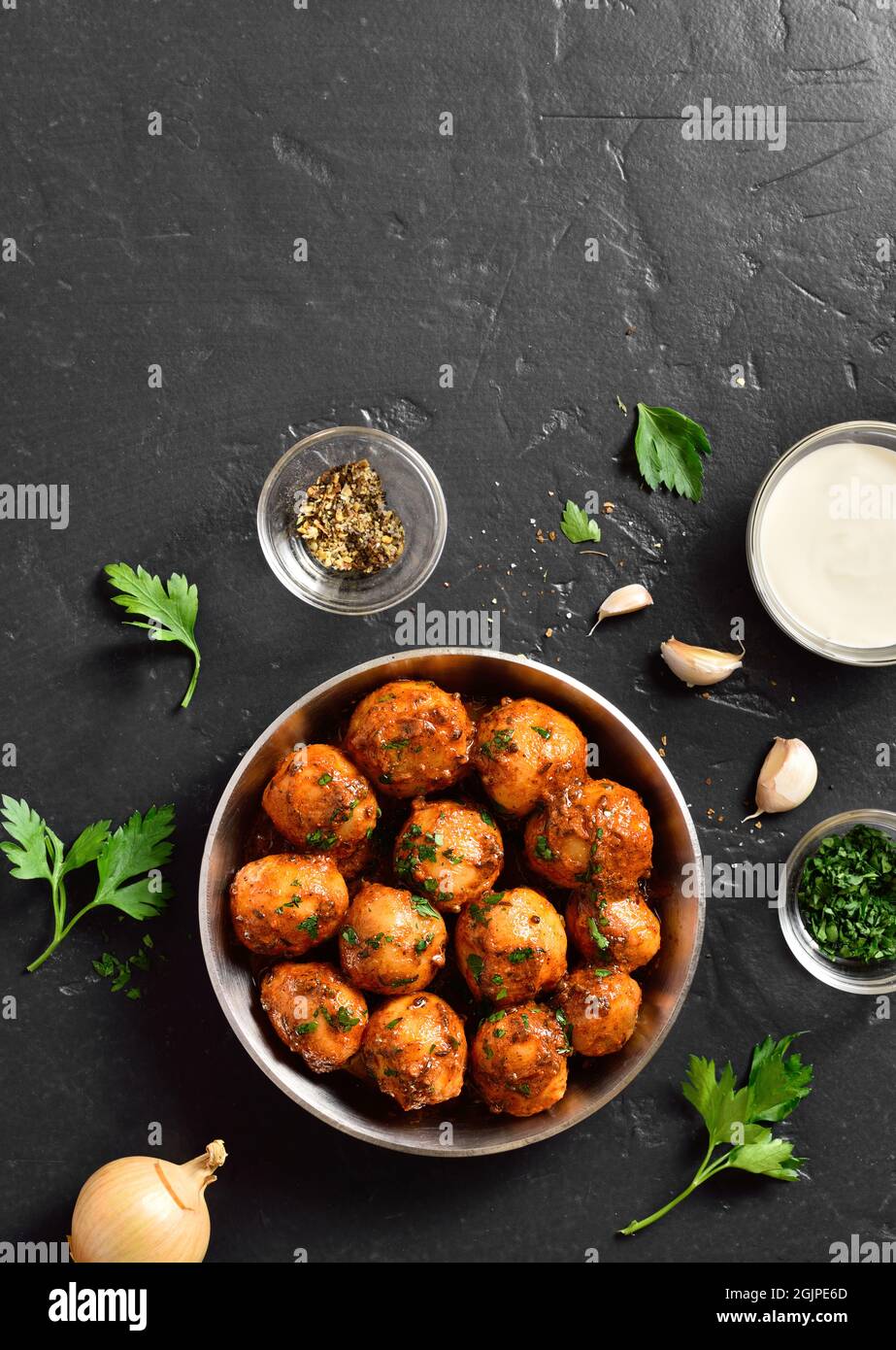 Patate Bombay. Pan patate fritte piccolo bambino con i semi di jeera e coriandolo in ciotola su sfondo scuro con spazio libero di testo. Popolare piatto indiano. Foto Stock