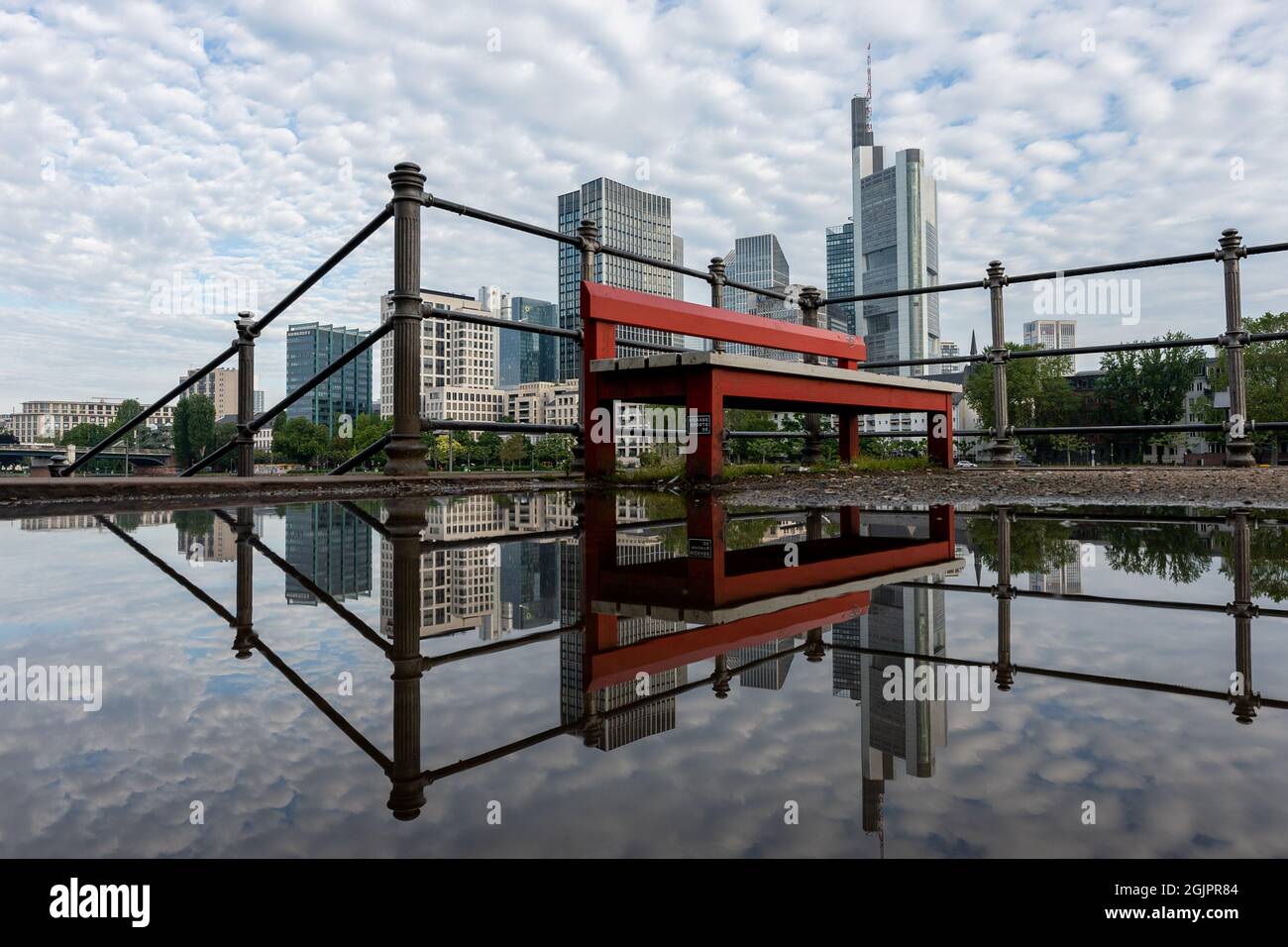 Francoforte, Germania - 4 giugno 2021: La famosa panchina rossa di fronte allo skyline di francoforte sul lungofiume principale Foto Stock