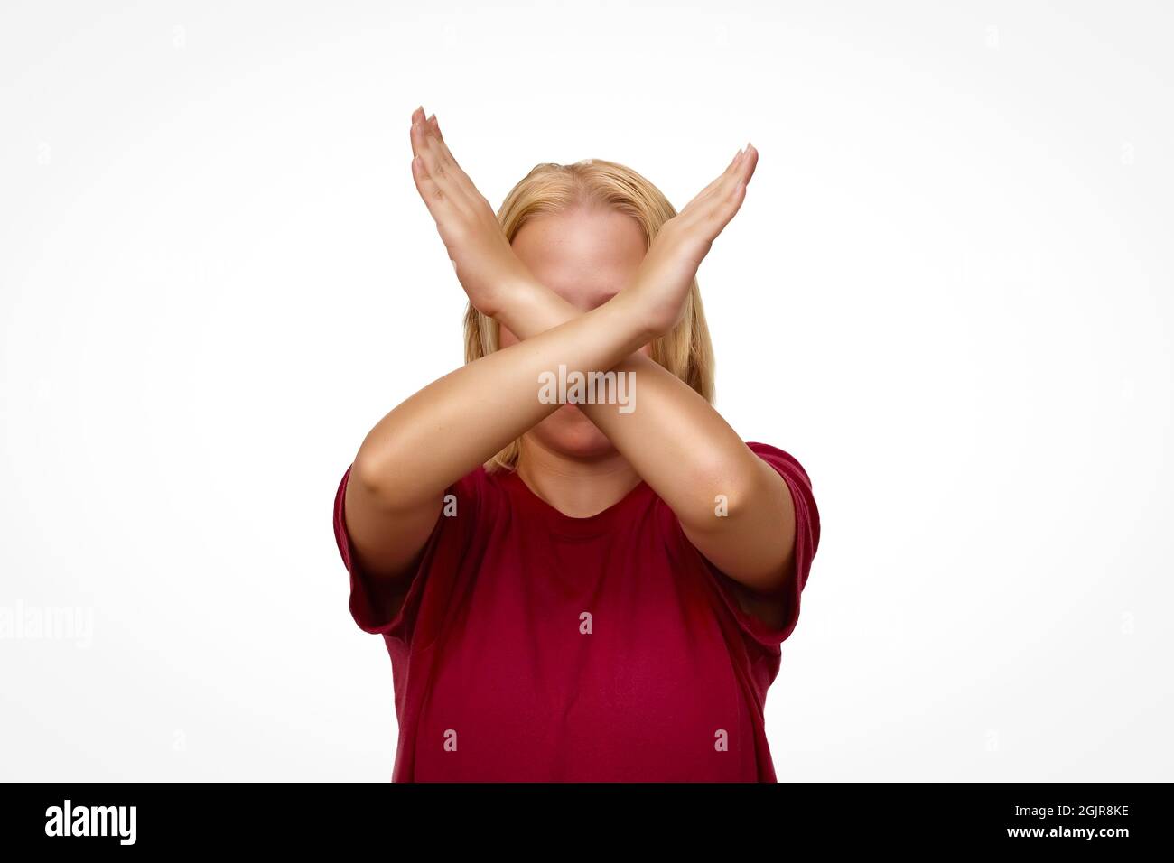 Ragazza con le braccia incrociate di fronte al viso isolato su sfondo bianco Foto Stock