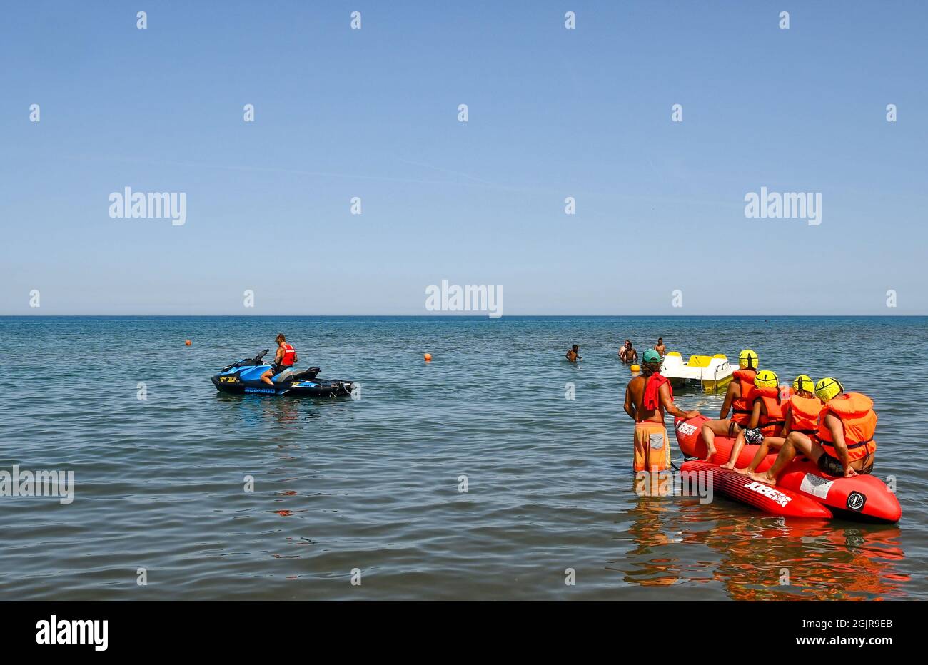Una famiglia di quattro persone che si divertono su un gommone trainato sul mare da una moto d'acqua in una soleggiata giornata estiva, Marina di Castagneto Carducci, Livorno, Toscana Foto Stock
