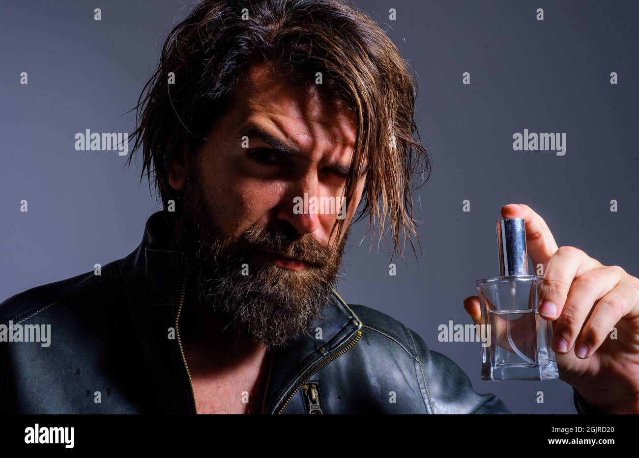 Uomo bearded con profumo. Fragranza maschile e profumeria. Bel ragazzo con bottiglia di colonia. Cosmetici uomo. Foto Stock