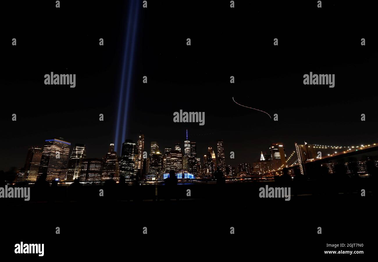 La gente guarda l'installazione di Tribute in Light e il World Trade Center nel 20° anniversario degli attacchi del 11 settembre, da Brooklyn, New York, Stati Uniti, 11 settembre, 2021. REUTERS/Mario Anzuoni Foto Stock