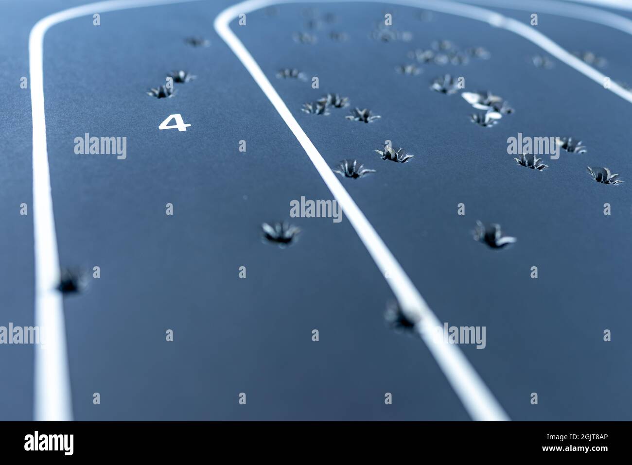Primo piano con una profondità di campo poco profonda di un bersaglio di silhouette in carta nera con più fori di pallottola all'interno. Foto Stock