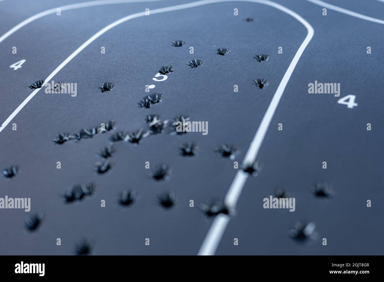 Primo piano con una profondità di campo poco profonda di un bersaglio di silhouette in carta nera con più fori di pallottola all'interno. Foto Stock