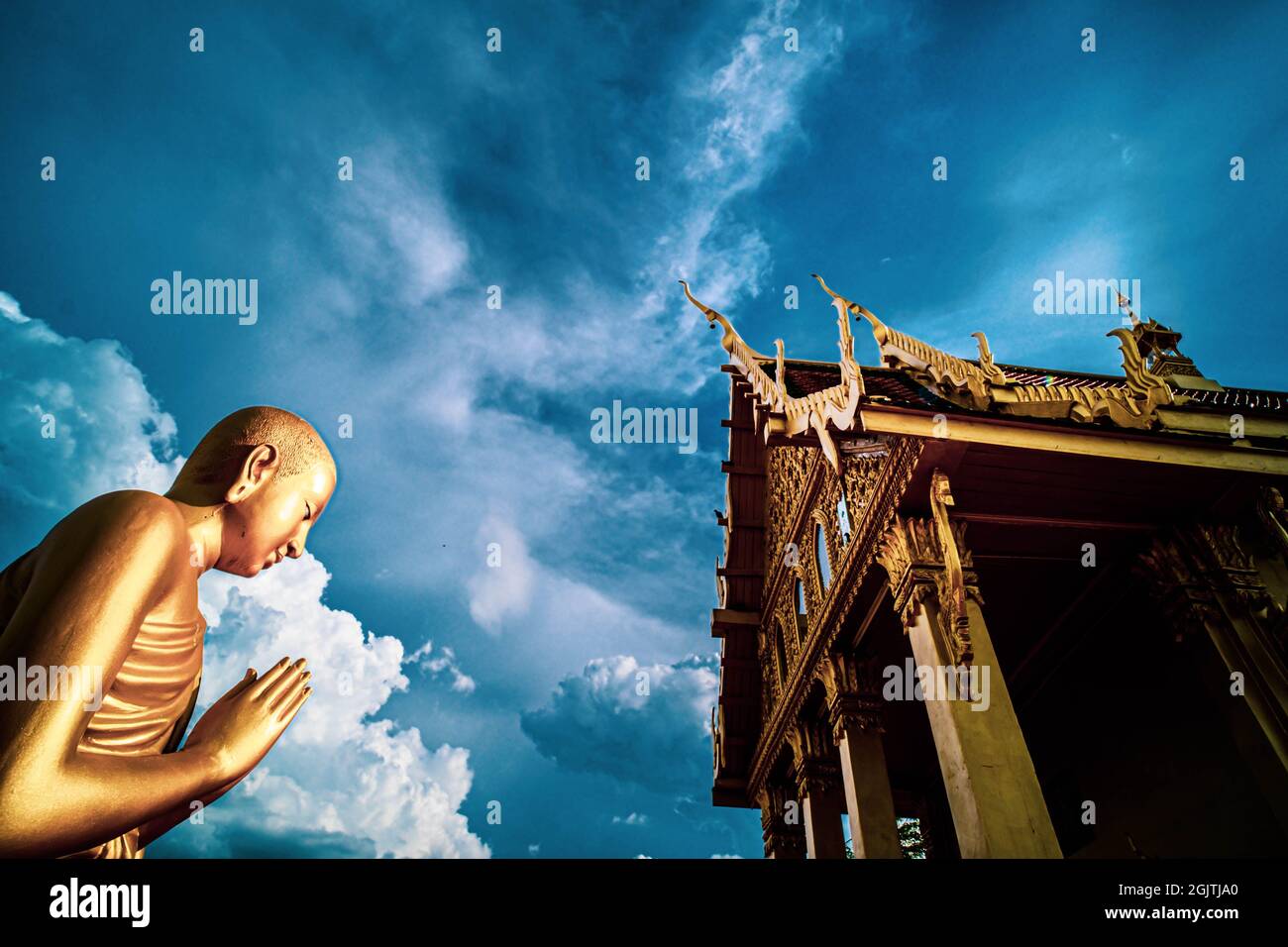 Statua e tempio del monaco d'oro, Thailandia Praying.Golden Standing Monk premere le mani insieme al petto o fronte in segno di rispetto Foto Stock