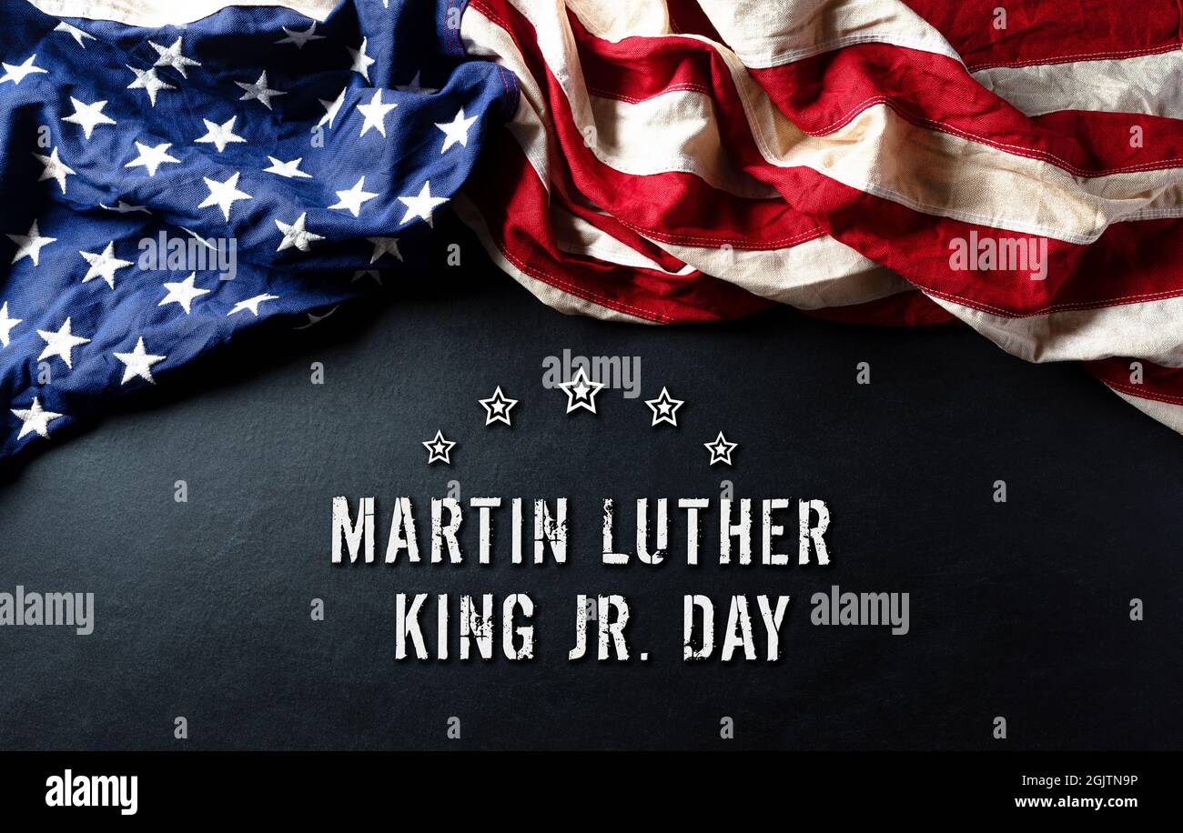 Martin Luther King Day anniversario concetto. Bandiera americana su sfondo di legno nero Foto Stock