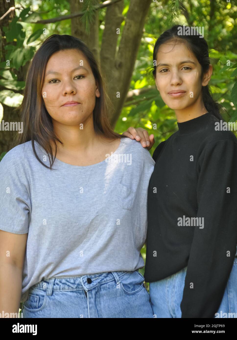 Ritratto di due belle ragazze del sud asiatico in posa all'aperto contro l'albero lesfy con guardare la macchina fotografica Foto Stock