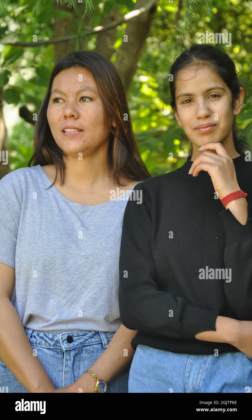 Ritratto di due belle ragazze del sud asiatico in posa all'aperto contro l'albero lesfy con guardare la macchina fotografica Foto Stock