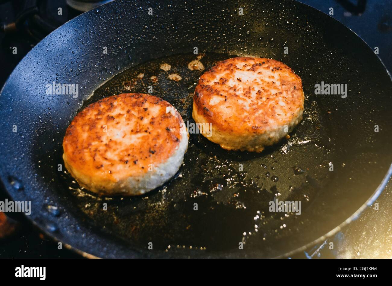 Due tagli rotondi di carne di manzo sono fritti in una padella e olio Foto Stock