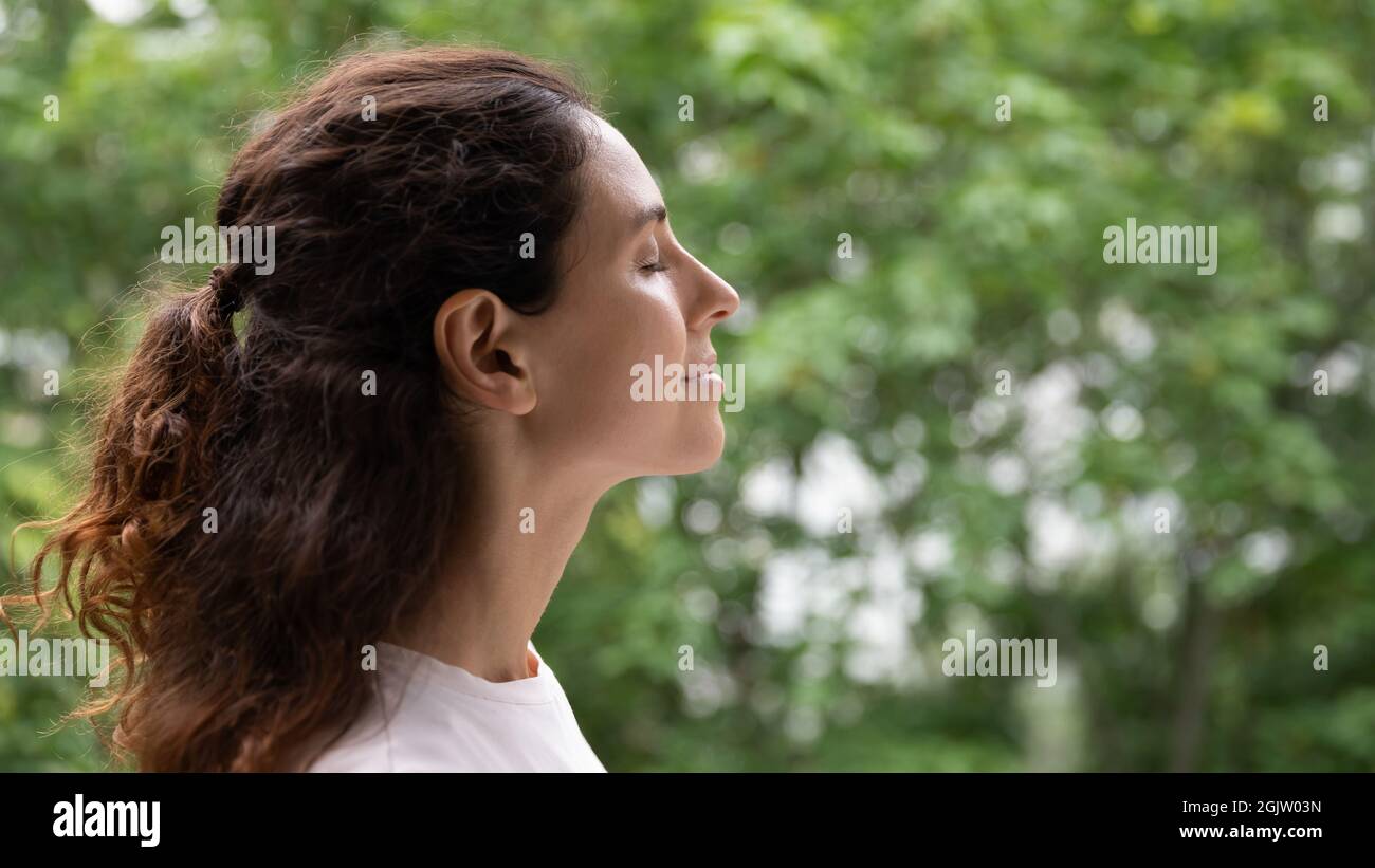 Vista laterale giovane donna serena in piedi all'aperto respirando aria fresca Foto Stock