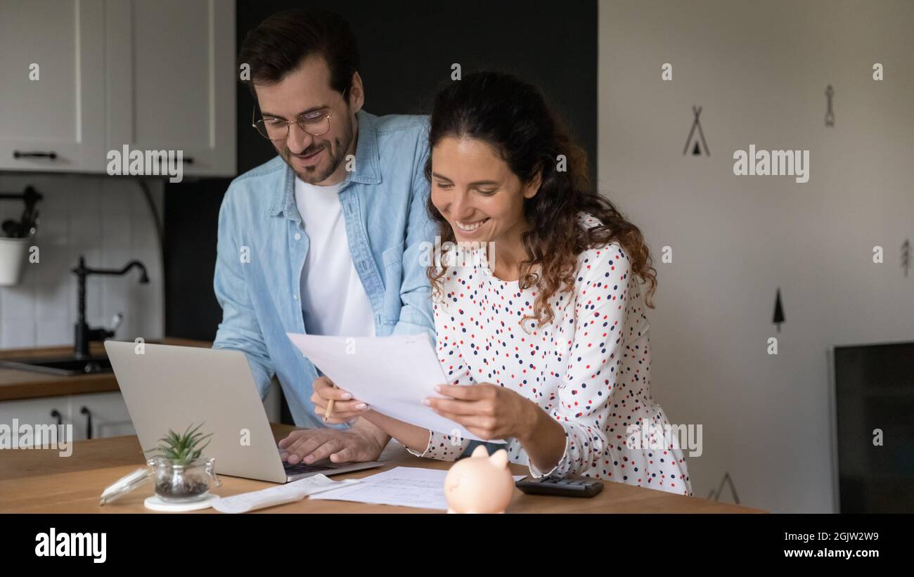 Famiglia felice gestire il bilancio di famiglia, lettura lettera di rimborso prestito Foto Stock