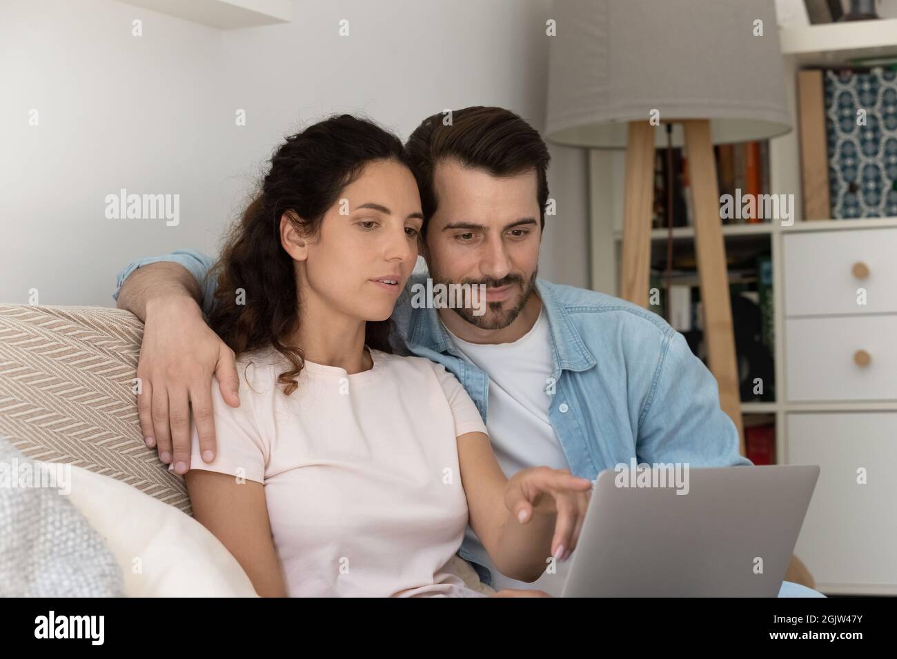 Coppia millennial seduta sul divano con notebook acquistare merci online Foto Stock