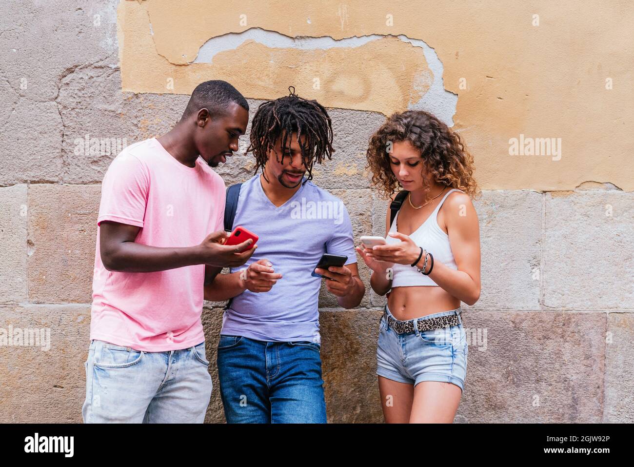 gruppo multietnico di giovani turisti che si alzano per strada controllando i loro telefoni Foto Stock