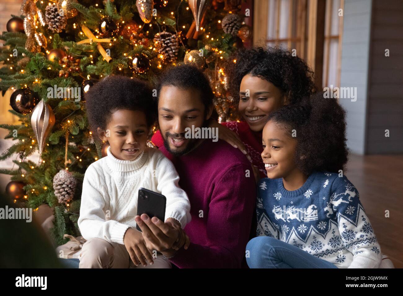 Buona famiglia biraciale con i bambini usano il cellulare insieme Foto Stock