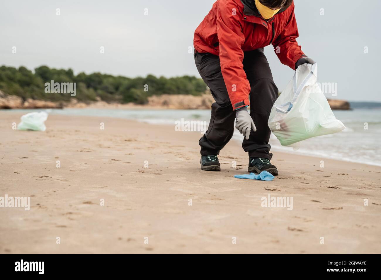 Giovane volontario pulisce plastica e rifiuti dalla spiaggia in spiaggia durante coronavirus pandemic - ambiente e ecologia problema concetto Foto Stock