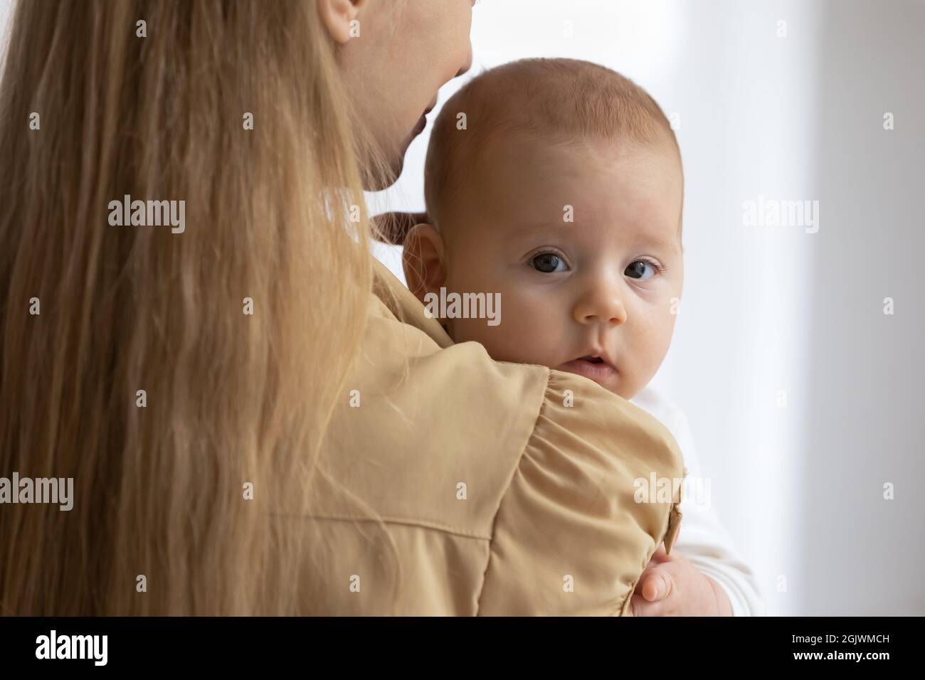 Ritratto del bambino piccolo carino che riposa nelle braccia felici delle madri Foto Stock