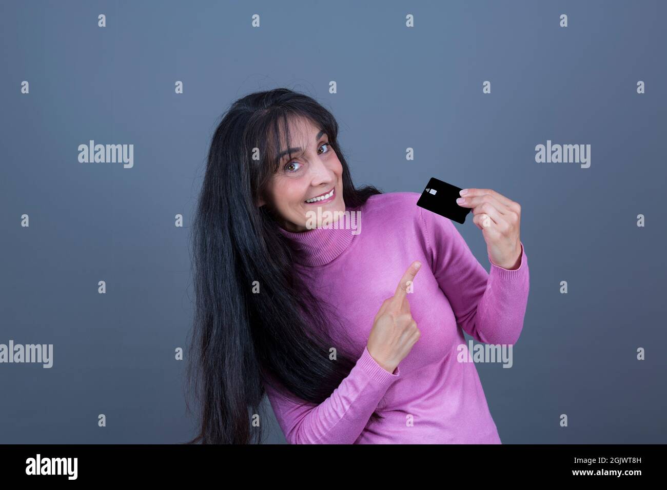 donna di 45 anni di successo e potenziata, bruna a capelli lunghi mostrando carta di credito. Foto Stock