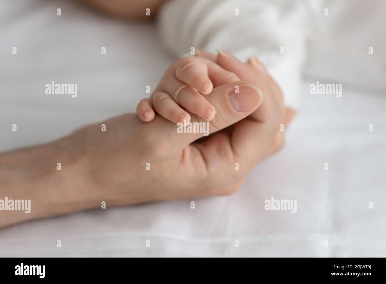 Nuova mamma che tiene la mano piccola del neonato che dorme Foto Stock