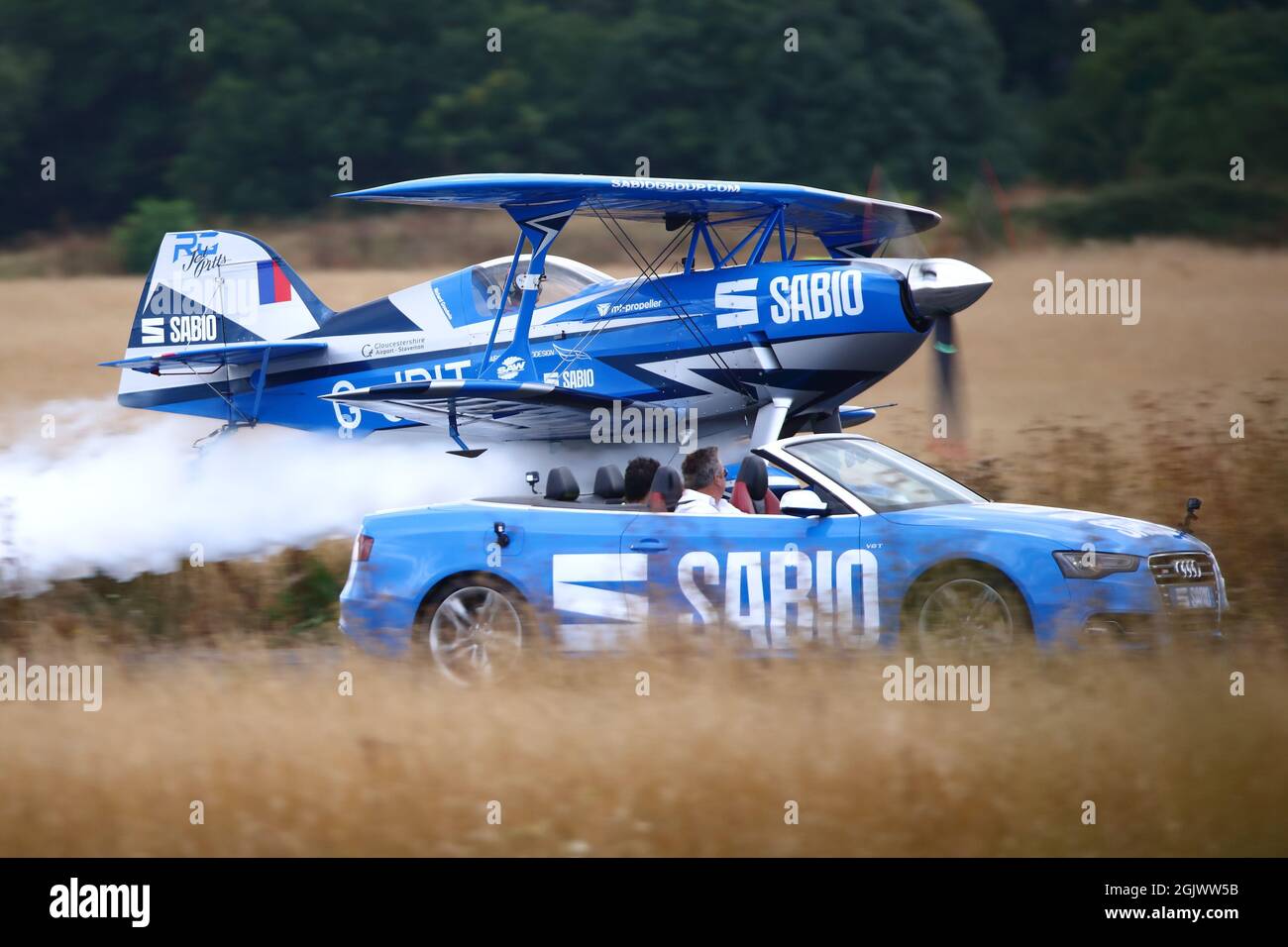 Rich Goodwin volare il suo blu Pitts Special biplanare G-JPIT accanto a un'auto sportiva Audi all'Abingdon Air & Country Show 2021 Foto Stock