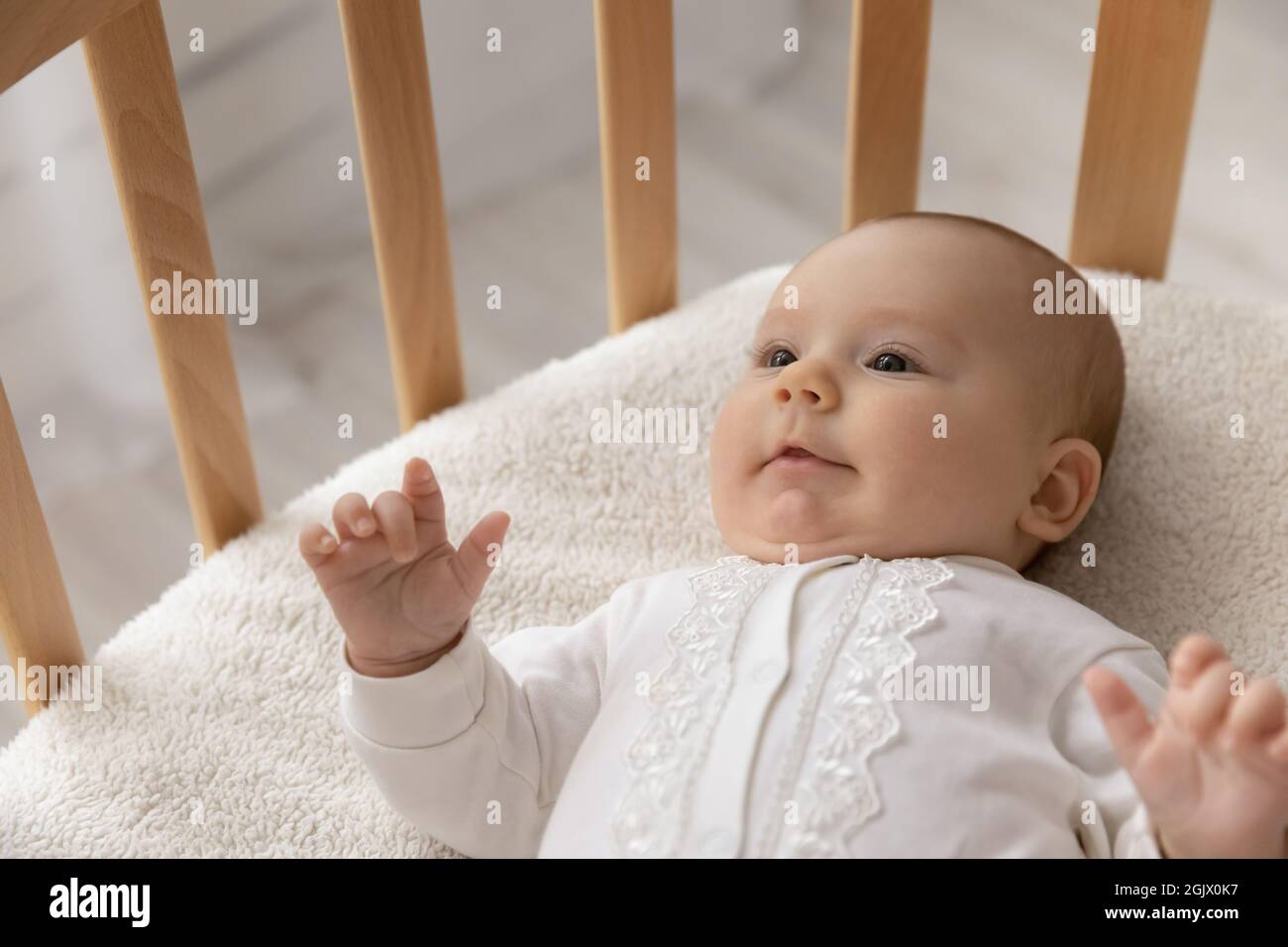 Sorridente piccolo carino pochi mesi bambino sdraiato in culla Foto Stock