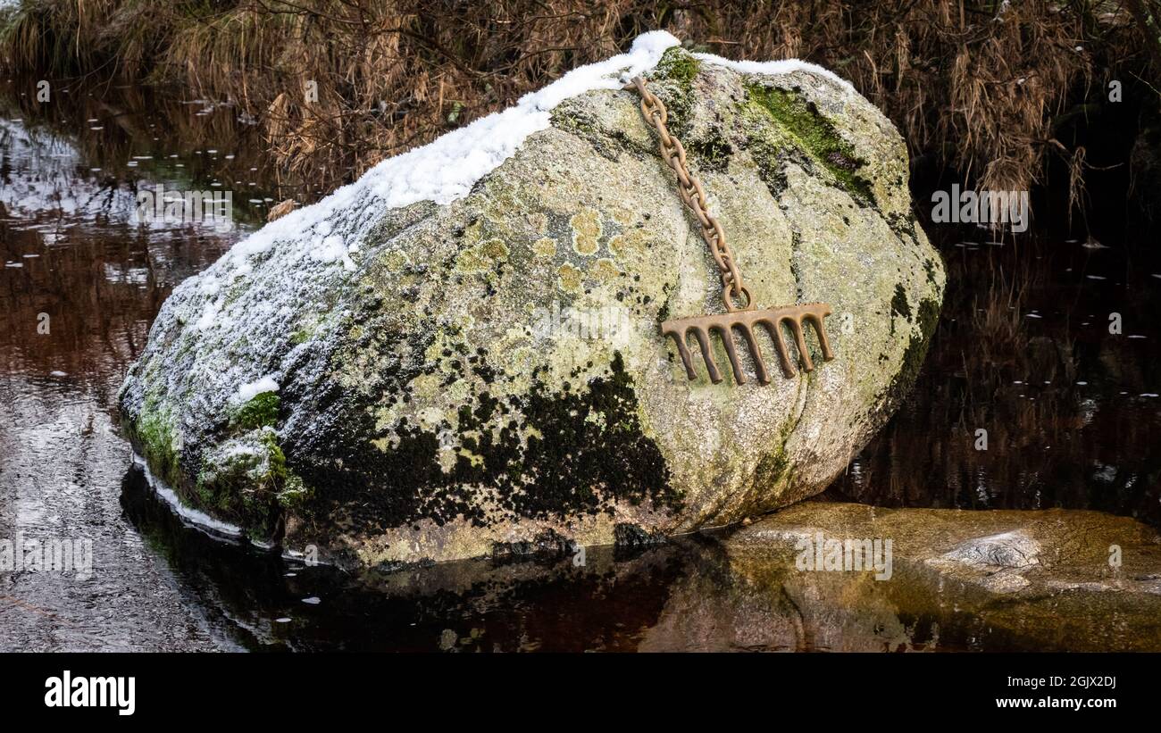 Un rastrello di bronzo attaccato ad un grande masso da una catena, coperta di neve in inverno, sulla Grande acqua del fiume Fleet al viadotto ferroviario, Galloway, SCO Foto Stock