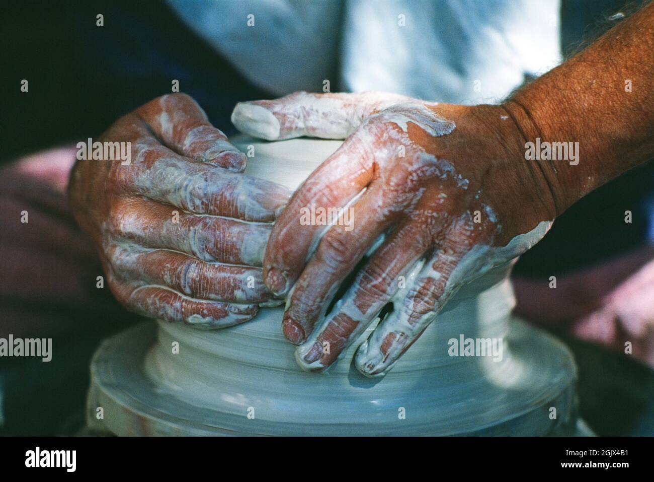 Primo piano delle mani dell'uomo gettando una pentola sulla ruota di un vasaio. Foto Stock