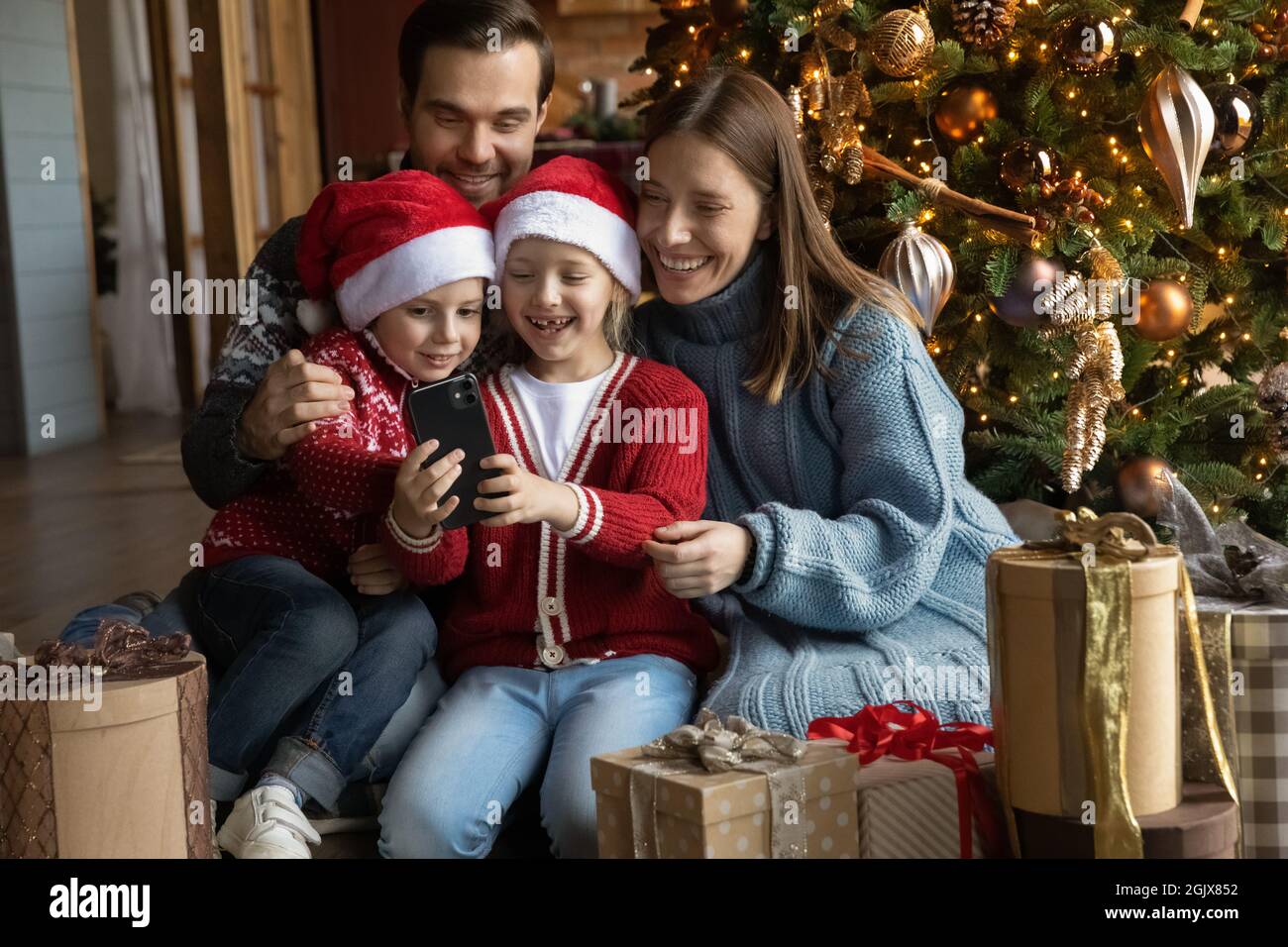 Famiglia felice in posa per le foto natalizie sullo smartphone. Foto Stock