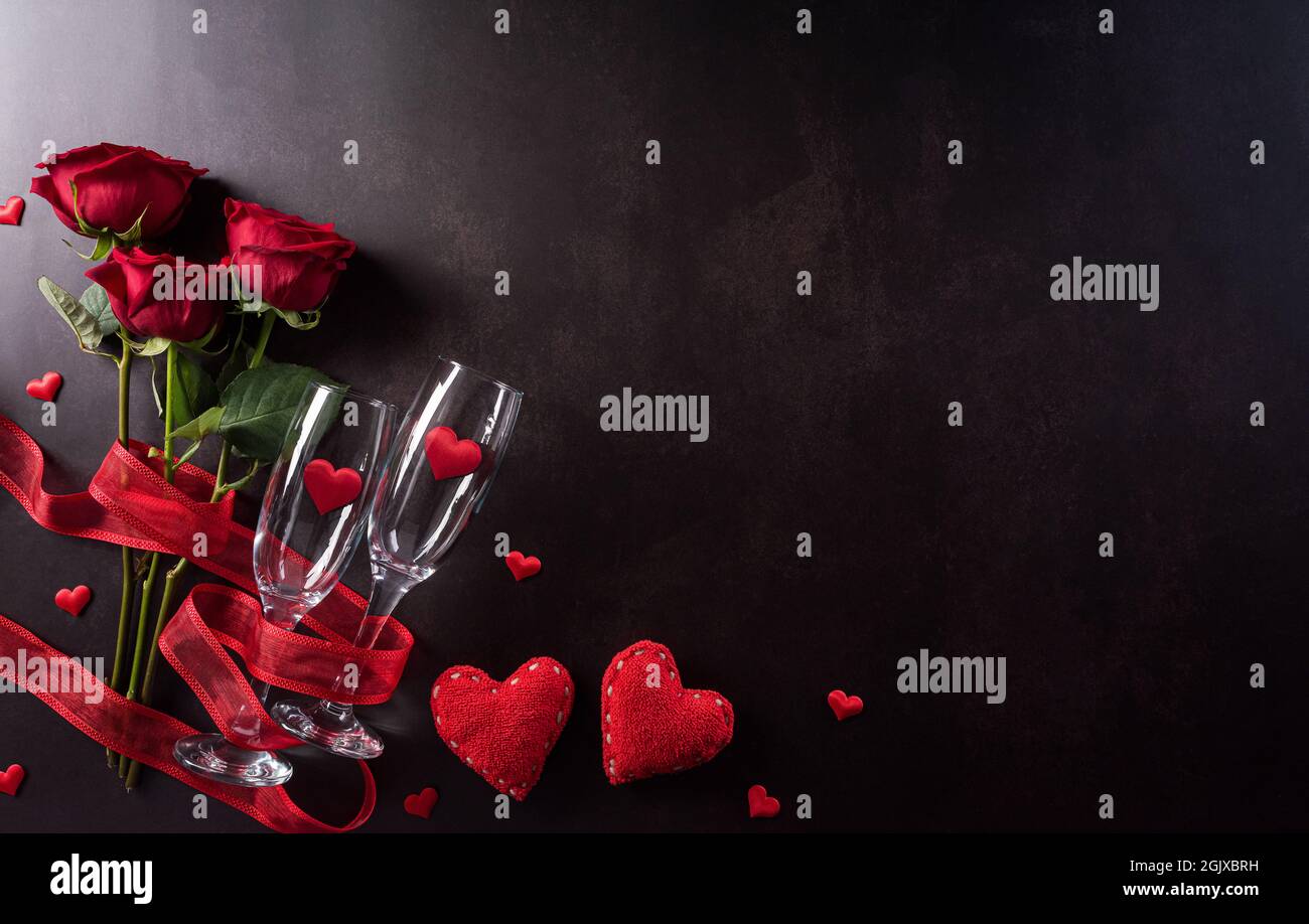 Il concetto Love and Valentine's Day è realizzato con bicchieri da champagne, cuori rossi e rosa su sfondo di pietra scura. Vista dall'alto con spazio di copia, disposizione piatta. Foto Stock