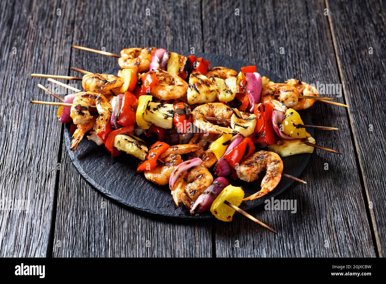 Gamberi Kabobs alla griglia con cipolla rossa, pepe dolce e ananas su un piatto di pietra nera Foto Stock